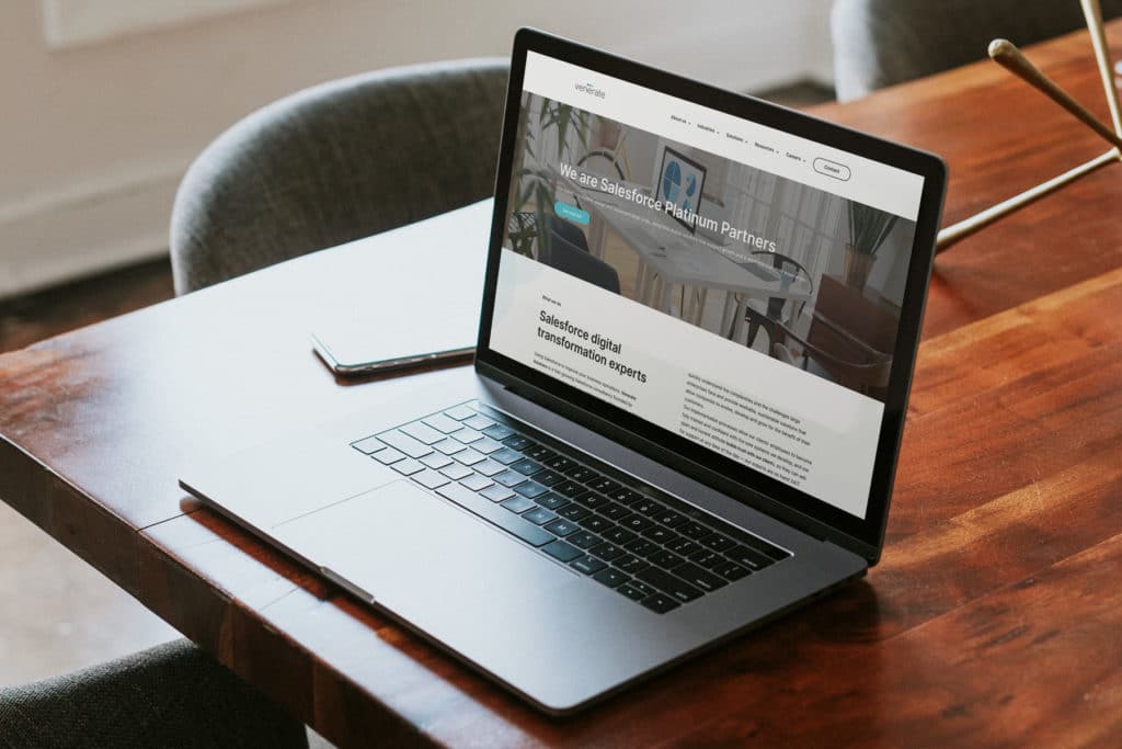 Venerate Solutions website shown on a laptop screen that sites on a wooden desk.