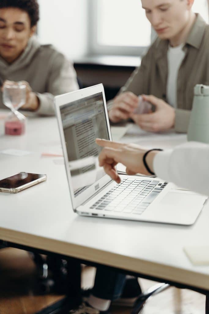 Image of a hand pointing at a laptop screen.